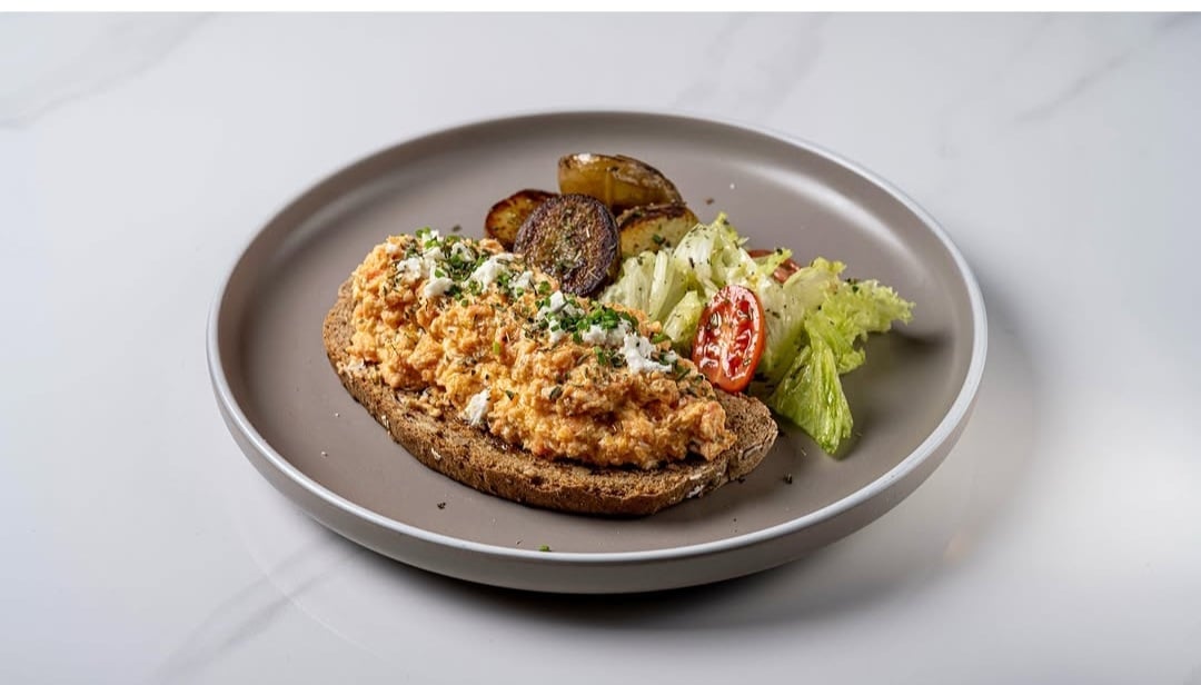 Golden-brown breaded cutlet with fresh vegetable garnish on a gray plate against a marble background